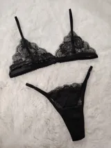 Conjunto de lencería de encaje negro, compuesto por un soutiene tipo triángulo con tirantes regulables y una bombacha colaless con tiras laterales ajustables mediante argollas metálicas.