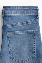 Jean skinny de tiro alto en denim azul claro, con diseño de cinco bolsillos y cierre frontal con botón y cremallera.