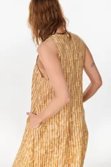 Vestido midi verde de lino italiano, con diseño sin mangas, cuello redondo y estampado de líneas onduladas punteadas. Cuenta con bolsillos laterales.