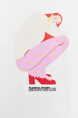 Camiseta blanca de corte oversize con cuello redondo y manga larga. Presenta una estampa gráfica central de una figura femenina, detalles estampados en la manga derecha y texto en la manga izquierda.