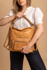 Cartera mochila color tostado, de cuero sintético, con compartimento principal amplio y bolsillos frontales con cierre. Tiene correas ajustables y asa superior para llevar al hombro o como mochila.