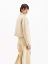 Chaqueta de gabardina color rosado con efecto desgastado, de calce relajado, cuello clásico marrón, bolsillos delanteros aplicados y cierre frontal con broches metálicos a presión.