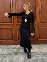 Vestido midi de color negro, confeccionado en tejido plisado con escote en V y mangas largas acampanadas.