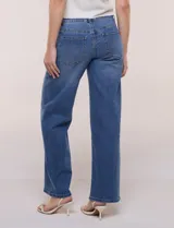 Jean de denim azul de tiro alto, corte wide leg con pierna ancha recta, con cinco bolsillos tradicionales, presillas para cinturón y cierre frontal con botón y cremallera.