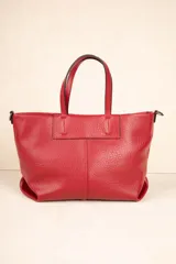Cartera tipo tote bag de símil cuero texturizado color rojo, con asas fijas y correa larga desmontable y regulable. Posee un bolsillo exterior con cierre metálico y tres compartimientos internos.