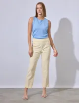Pantalón de vestir color crema con finas rayas verticales en amarillo pálido. Tiene bolsillos simulados en la parte delantera y corte recto.