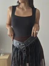Cinto tipo falda de cuero sintético negro con flecos largos y tachas plateadas.