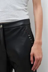 Pantalón de eco cuero negro, de corte recto, con tachas plateadas en los bolsillos delanteros.