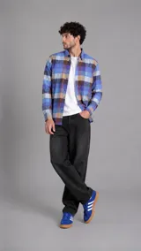 Camisa de manga larga con estampado a cuadros en tonos azules, violetas y marrones, con cuello clásico y cierre frontal de botones.