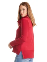 Buzo de punto color beige con cuello volcado amplio, mangas largas acanaladas y torso liso. Presenta una costura central vertical, ruedo con tajos laterales y largo asimétrico, siendo más largo en la parte posterior.