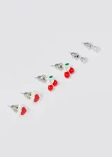 Set de tres pares de caravanas mini: un par con forma de corazón blanco con detalle rojo, un par con forma de cerezas rojas y un par con forma de cristal transparente.