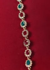 Pulsera dorada con eslabones de bronce y cristales rojos, verdes y blancos engarzados en forma floral.