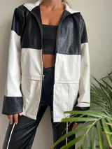 Campera con capucha, de cuero sintético, con diseño color block en blanco y negro y cierre frontal.