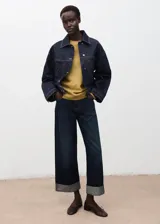 Sweater de punto fino en color mostaza, con cuello redondo y diseño oversize de manga larga. Presenta un acabado de canalé en los puños y el ruedo.