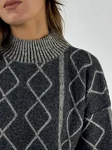 Sweater de lana color bordó con cuello alto y diseño de rombos y líneas verticales en rojo. Tiene puños y dobladillo acanalados.