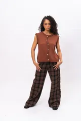 Chaleco de punto color marrón, sin mangas, con cuello redondo y cierre frontal asimétrico con botones. Presenta un diseño tejido con textura acanalada en los bordes.