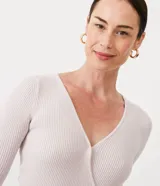 Blusa de punto color lila claro, ajustada al cuerpo, con escote cruzado en V y mangas tres cuartos.