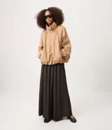 Campera bomber de sarga color beige, con diseño cortavientos, cuello alto con botones a presión y cierre frontal. Presenta mangas largas con puños elastizados, pliegues delanteros que aportan volumen y ruedo con elástico. Marca Renner.