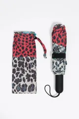 Paraguas plegable con diseño patchwork de animal print en tonos beige, azul y rosado. Incluye funda protectora con el mismo estampado y mango negro con el nombre de la marca grabado.