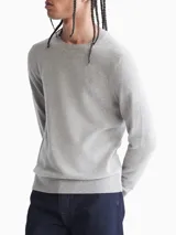 Sweater de punto liso color gris melange, con cuello redondo y puños y dobladillo en punto canalé. Presenta un pequeño logo bordado en el pecho.