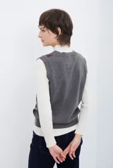 Chaleco de punto con diseño de rombos en tonos beige, marrón y gris. Presenta cuello redondo y corte ajustado a la cintura.