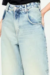 Pantalón de denim de tiro alto, corte wide leg y lavado claro con efecto desgastado. Cuenta con diseño de cinco bolsillos y presillas para cinturón.