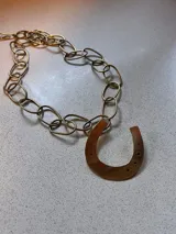 Collar de cadena de eslabones gruesos con dije colgante en forma de herradura.