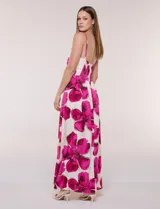 Vestido maxi de fondo blanco con estampado de flores grandes en tonos verde y marrón, con escote en V, breteles finos y detalle de abertura cut-out en el centro del busto.