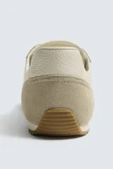 Zapatilla deportiva estilo barefoot, color marrón, con diseño de puntera ancha y redondeada. Confeccionada en una combinación de materiales textiles y detalles en serraje. Cuenta con suela fina de goma flexible y cordones en color crema.