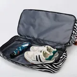 Bolso deportivo de viaje marca Zuomanni, con estampado animal print de leopardo en blanco y negro. Cuenta con doble asa de mano, correa de hombro ajustable y extraíble, y un compartimento inferior independiente con cierre.