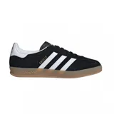 Championes Adidas Gazelle Indoor de diseño clásico, confeccionados en gamuza negra con las icónicas tres tiras laterales en blanco. Presentan el nombre del modelo en letras doradas, talón en contraste blanco y suela de goma color caramelo.