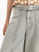 Pantalon de denim tiro medio color gris, con diseño amplio y costuras decorativas frontales. Cuenta con pasacintos, bolsillos y cierre frontal con botón.