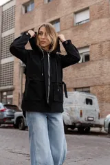 Gabardina liviana color beige con capucha, cierre frontal oculto y cintura ajustable mediante cordón. Presenta bolsillos delanteros amplios y mangas largas con puños rectos.