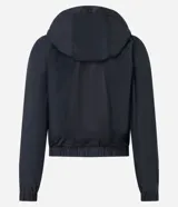 Campera rompevientos deportiva blanca, confeccionada en poliamida, con capucha, cierre delantero en cremallera, tirador gomoso y puños ajustados.