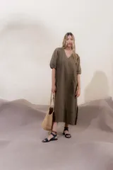 Vestido largo azul oscuro de lino 100% con escote en V, mangas abullonadas con elástico en el puño y pespunte en contraste. Presenta detalle de punto smock en el canesú y bolsillos laterales.