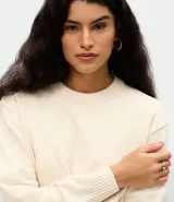 Suéter de tejido chenille con cuello redondo acanalado, mangas largas y puños reforzados. Presenta un corte regular y una textura suave y aterciopelada.