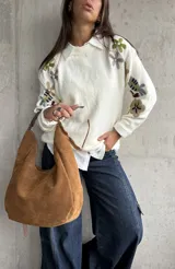Sweater de punto color natural con cuello redondo y mangas largas, decorado con bordados florales multicolores en las mangas y hombros.