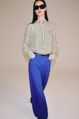Jeans de tiro medio y corte barrel leg, de color azul, con diseño de cinco bolsillos y trabillas en la cintura. Cierre frontal con cremallera y botón metálico.