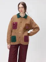 Campera tejido grueso y abrigado color verde militar, con forro de nylon interno, cuello estilo camisa en color negro y cierre frontal con botones. Cuenta con cuatro bolsillos delanteros con apliques en distintos tonos y texturas, y un parche bordado circular en el bolsillo superior izquierdo.