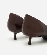 Zapato tipo scarpin con tacón kitten heel, confeccionado en poliuretano con textura símil cuero. Presenta punta fina y un diseño con recorte asimétrico en el empeine.