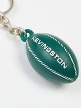Llavero con dije en forma de pelota de rugby color verde, con el nombre de la marca Kevingston grabado en blanco.