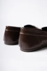 Mocasín de cuero marrón con textura arrugada, diseño de puntera cuadrada con detalle de costuras fruncidas en los laterales y banda frontal clásica.