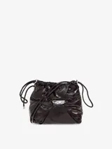 Bolso tipo cubo para mujer, confeccionado en cuero brillante color marrón oscuro, con efecto arrugado o 'aplastado' alrededor del logotipo metálico 'D' de Diesel. Posee cordones y una correa ajustable, y múltiples bolsillos internos.