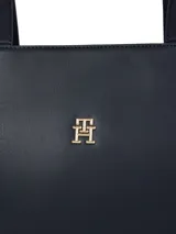 Cartera shopper azul marino de Tommy Hilfiger, confeccionada en poliuretano con doble asa superior y cierre de cremallera. Presenta el logotipo metálico de la marca en la parte delantera.