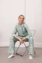 Conjunto de pijama de dos piezas, color verde menta con estampado de cuadros irregulares en blanco. Incluye camisa de manga larga con botones y pantalón largo con cintura elástica.
