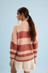 Buzo de algodón tejido a mano, de calce relajado y cuello redondo, con diseño gráfico inspirado en carpas de playa y franjas horizontales en tonos rosado, marrón, celeste y amarillo.