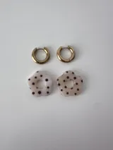 Aros de acero quirúrgico dorados con argollas pequeñas y dijes colgantes en forma de flor color celeste.