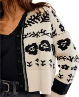 Cárdigan de punto con cuello tipo camisa y cierre frontal de botones. Presenta un diseño estampado floral en contraste sobre fondo claro, con puños y ruedo acanalados.