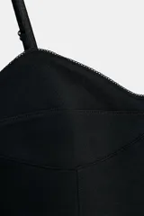 Body negro de corte ajustado, con escote corazón y ribete de encaje o festón en el borde superior. Posee tirantes finos ajustables y cierre de broches en la parte inferior.