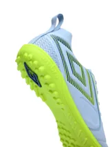 Championes de fútbol 5 Umbro modelo Vision TF para hombre, en color celeste con suela y detalles en verde lima. Presenta el logo de la marca en el lateral con diseño de rayas y cordones tono sobre tono.